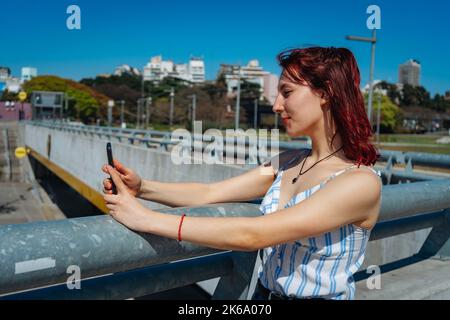 Una giovane donna dai capelli rossi che prende un selfie con il suo telefono cellulare. Spazio di copia. Orientamento orizzontale. Foto Stock