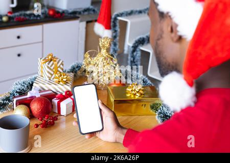 Uomo afroamericano che indossa il cappello di santa, che usa lo smartphone con il copyspace Foto Stock