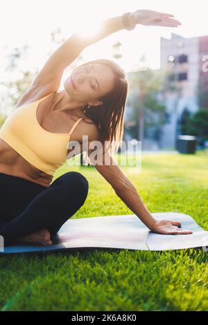 Bella donna che fa esercizi durante la registrazione di vlog sportivi, utilizzando la fotocamera su treppiede all'aperto. Natura estiva. Stile di vita all'aperto. Attivo sano Foto Stock