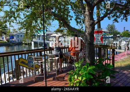 La gente gode della vista sul canale di barche e moli mentre beve all'aperto presso il ristorante e bar Phuzzys Boat Shack a St. James City, Pine Island, Florida Foto Stock