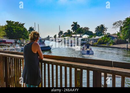 Donna guarda dal molo del canale affollato con i boaters di festa vicino Phuzzy's Boat Shack ristorante & bar a St. James City, Pine Island, Florida Foto Stock