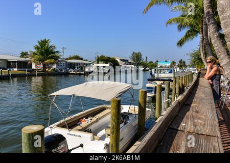 Donna che guarda il traffico delle barche dei canali e le barche attraccate accanto al ristorante e bar Phuzzys Boat Shack a St. James City, Pine Island, Florida Foto Stock