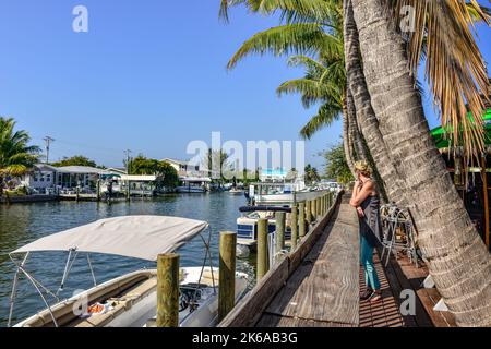 Donna che guarda il traffico delle barche dei canali e le barche attraccate accanto al ristorante e bar Phuzzys Boat Shack a St. James City, Pine Island, Florida Foto Stock