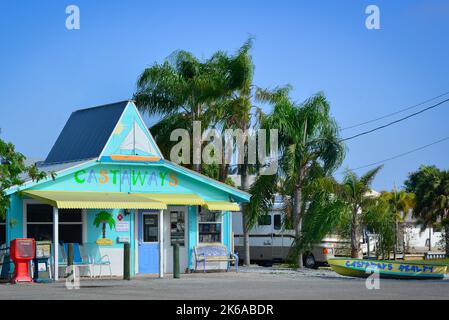 Un affascinante piccolo edificio in colori pastello ospita il Castaways Realty business con barca parcheggiata di fronte a St. James City, Pine Island, Florida, Stati Uniti Foto Stock