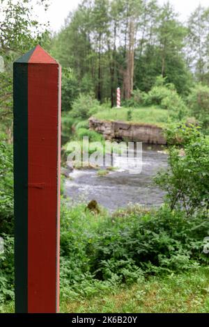 Pali di frontiera sulla linea di confine tra Polonia e Bielorussia sul fiume Svisloch. Scatto verticale. Focus sul polo di confine bielorusso. Foto Stock