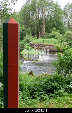 Pali di frontiera sulla linea di confine tra Polonia e Bielorussia sul fiume Svisloch. Scatto verticale. Focus sul polo lucido. Foto Stock