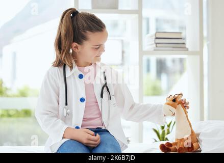 Youre tutto meglio ora. Una bambina che finge di essere un medico mentre esamina il suo animale farcito a casa. Foto Stock