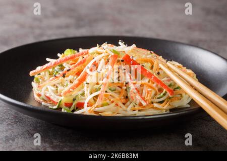 L'insalata Kani è un'insalata di pesce di stile giapponese preparata con il closeup del bastone di granchio nel piatto sul tavolo. Orizzontale Foto Stock