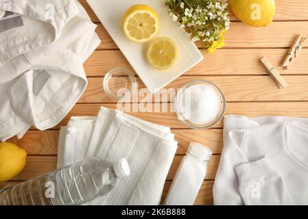 Rimedio domestico per lavare i vestiti in modo sostenibile e naturale con limone, bicarbonato e aceto con i vestiti su un tavolo di legno. Vista dall'alto. Orizzonte Foto Stock