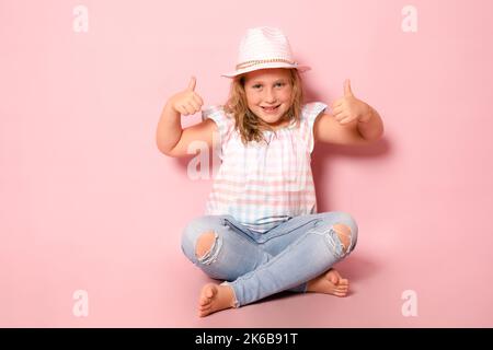 Foto di allegra giovane ragazza giovane felice fare le dita pollici su sorriso raccomandare isolato su sfondo rosa Foto Stock