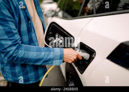 Sezione centrale dell'uomo che collega il caricabatterie all'auto elettrica Foto Stock