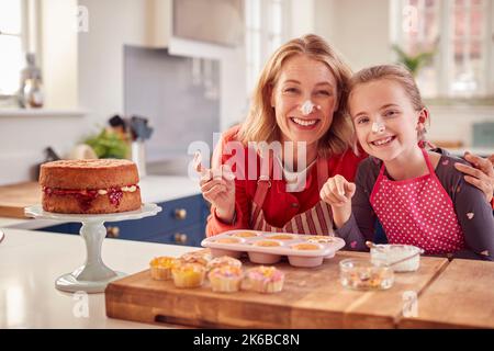 Ritratto di nonna con nonna cottura Cupcakes e mettere glassa sul naso a casa Foto Stock