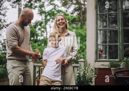 Padre e madre giocano con un figlio felice mentre sono in cortile Foto Stock