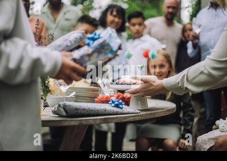 Mani di donna che tengono decorato torta di compleanno sul tavolo Foto Stock