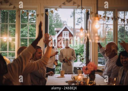 Famiglia felice con le mani alzate che si divertono mentre gioca durante la festa a casa Foto Stock