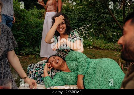 Felici amici femminili seduti e godendosi alla festa in giardino Foto Stock