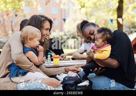 Le madri giocano con le figlie seduti al parco Foto Stock