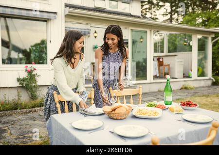 Sorribili sorelle che allestiscono un tavolo nel cortile posteriore Foto Stock