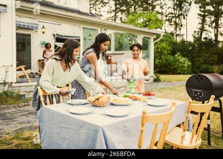 Fratelli che impostano il cibo sul tavolo nel cortile posteriore Foto Stock