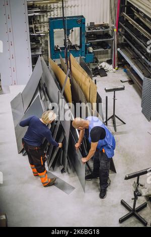 Vista ad angolo elevato di carpentieri maschi e femmine che lavorano insieme in officina Foto Stock