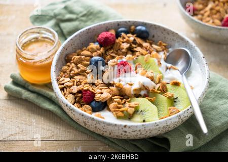 Ciotola di grano al miele OAT con frutta e yogurt su un tavolo di legno Foto Stock