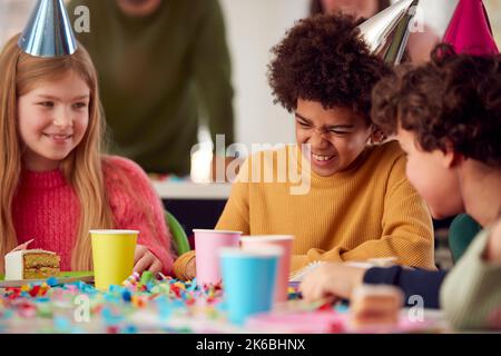 Bambini seduti al tavolo amici che festeggiano alla festa di compleanno con gli amici a casa Foto Stock