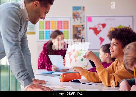 Gruppo di studenti multiculturale con insegnanti in aula che guardano la mappa nella lezione di Geografia Foto Stock