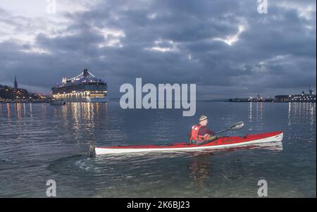 Cobh, Cork, Irlanda. 13th ottobre 2022. Il kayak Paddy o' Donovan si dirige verso la sua pagaia mattutina quotidiana intorno a Spike Island mentre la nave da crociera Norwegian Dawn arriva prima dell'alba a Cobh, Co. Cork, Irlanda. - Credit; David Creedon / Alamy Live News Foto Stock