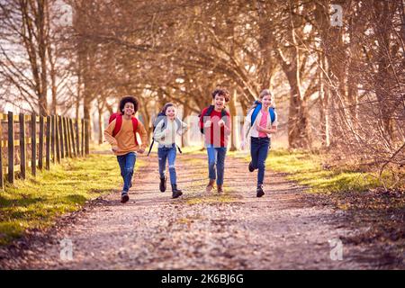 Ritratto Bambini con zaini scolastici all'aperto che corrono lungo il percorso della campagna Foto Stock