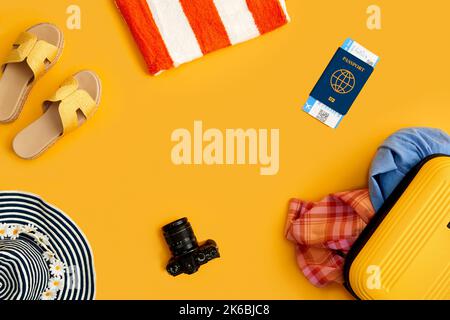 Flat Lay Shot di valigia gialla disimballata con accessori per le feste su sfondo giallo Foto Stock