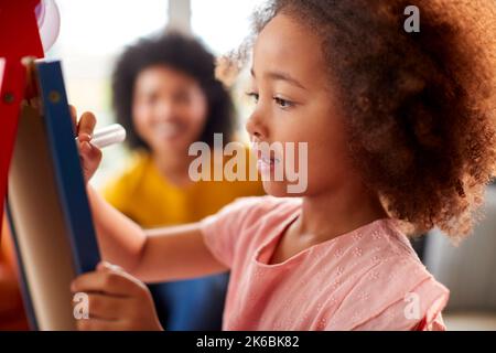 Madre e figlia hanno divertente disegno immagine sulla lavagna a casa insieme Foto Stock