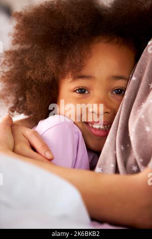 Primo piano Ritratto di figlia che abbraccia la madre indossando pigiami a letto a casa Foto Stock