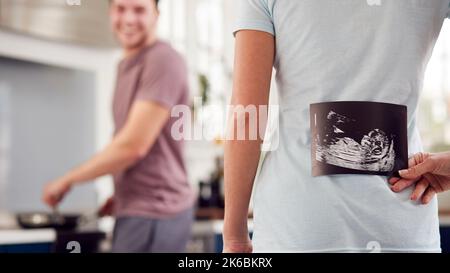 Coppia incinta Transgender a casa in cucina con Donna uomo sorprendente con scansione ecografica del bambino Foto Stock