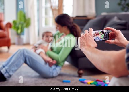 Punto di vista scatto del Padre scattare l'immagine della madre che gioca con il bambino Son sul telefono mobile Foto Stock