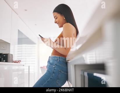 Ammalo essere LOLing tutto il giorno. Una giovane donna che usa il suo cellulare a casa. Foto Stock