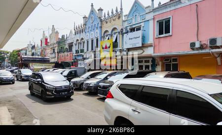 Vista delle auto in movimento e del parcheggio e dei negozi presso l'affollato mercato tradizionale 'Pasar Modern BSD'. Foto Stock