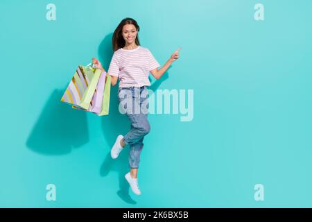 Foto a grandezza naturale di una bellissima donna con T-shirt a righe di capelli marroni che indica uno spazio vuoto isolato su sfondo di colore turchese Foto Stock