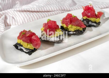 Antipasto Milfey tonno. Nori millefeuille, guacamole, tonno su sfondo bianco per il menu del ristorante. Foto Stock