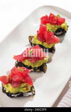 Antipasto Milfey tonno. Nori millefeuille, guacamole, tonno su sfondo bianco per il menu del ristorante. Foto Stock