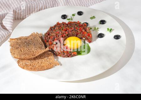 tartaro di manzo con capperi e piccoli toast su sfondo bianco per il menu del ristorante. giacitura piatta Foto Stock