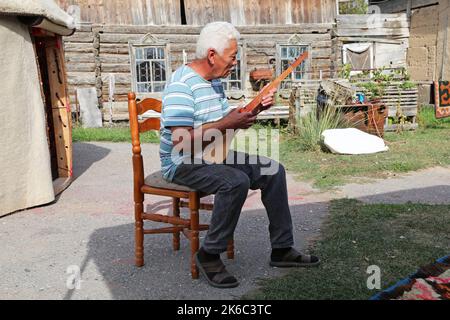 Suonare un tradizionale Komuz fatto a mano, laboratorio di AK-Orgo, Barskoon, Regione di Issyk Kul, Kirghizistan, Asia centrale Foto Stock