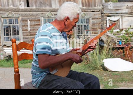 Suonare un tradizionale Komuz fatto a mano, laboratorio di AK-Orgo, Barskoon, Regione di Issyk Kul, Kirghizistan, Asia centrale Foto Stock