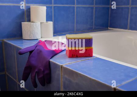 Guanti di gomma e spugne all'interno del bagno. Set di accessori colorati per la pulizia della casa. Casa pulita. Vista frontale Foto Stock