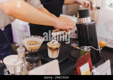 Barista spruzzare a mano il cacao in polvere sul cioccolato ghiacciato. Foto Stock