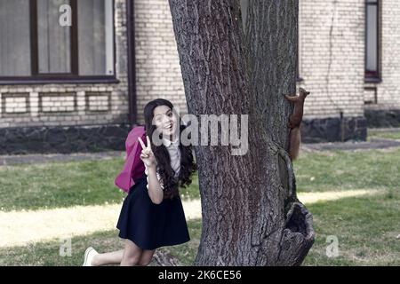 Appassionato di Zoologia. Felice bambino mostrare segno di pace. Scoiattolo rosso salita tronco albero. Scienza animale. Zoologia. Ritorno a scuola. Naturale Foto Stock