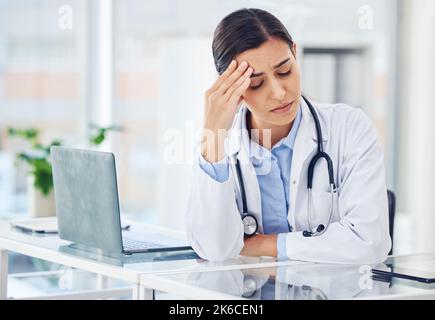 Anche i medici hanno difficoltà: Un giovane medico che guarda ha sottolineato quando lavora in un ufficio medico. Foto Stock