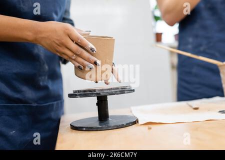 Vista ritagliata di donna afroamericana che tiene prodotto di argilla in studio di ceramica, immagine stock Foto Stock