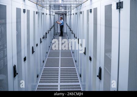 13 ottobre 2022, Sassonia, Taucha: Michael Freitag, Group Manager Data Center Management, controlla i cabinet dei server nel nuovo data center di Datacenter Leipzig. Lo stesso giorno, il primo nodo Internet regionale per gli stati tedeschi di Brandeburgo, Sassonia, Sassonia-Anhalt e Turingia è andato online qui. DE-CIX Leipzig è integrato nel più grande ecosistema di interconnessione neutrale del mondo, collegando oltre 2.500 operatori di rete, provider di servizi Internet, provider di contenuti e reti aziendali di oltre 100 paesi. Il nodo, gestito dall'operatore di rete in fibra ottica Envia Tel, è 1 Foto Stock