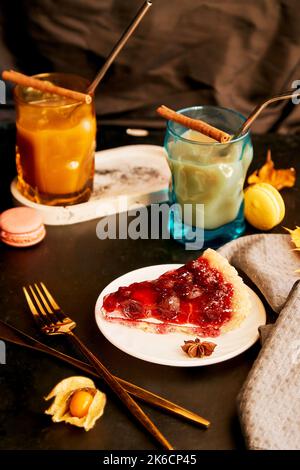 Bicchieri creativi di latte di zucca, bastoncini di cannella e torta di ciliegie. Caffè stagionale in autunno. Estetica accogliente casa. Foto Stock