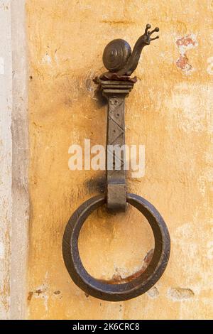 Cavallo arrugginito anello di aggancio su un vecchio muro di pietra a forma di lumaca Foto Stock